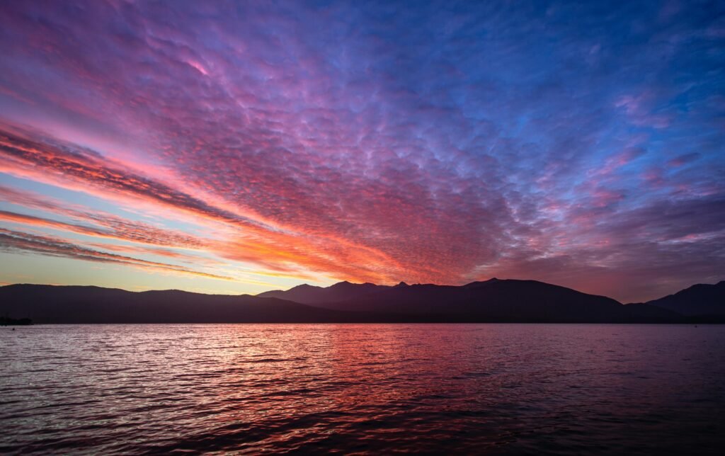 A breathtaking sunset with vibrant sky colors over a tranquil lake in New Zealand.